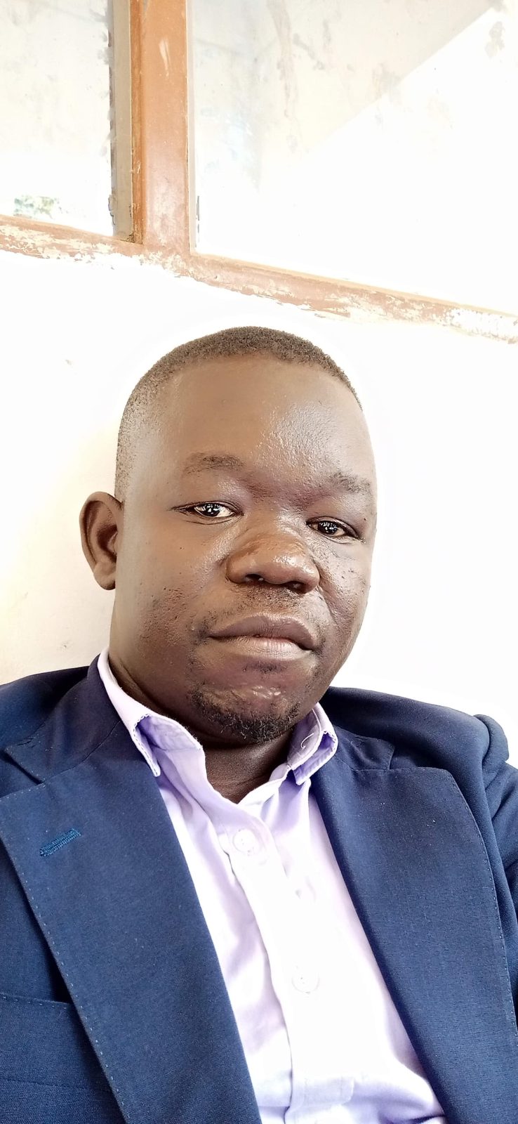 Tabu Sam, founder of Artzon, poses at his printing and branding business in Arua City, showcasing locally driven entrepreneurship and innovation in Uganda.