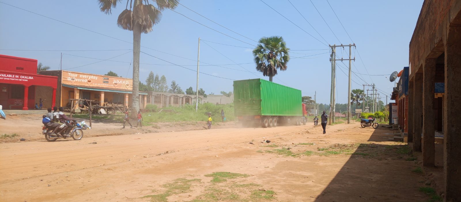 Heavy trucks from Kenya travel through the dusty unpaved road in Onduparaka, Arua City, heading toward the Democratic Republic of Congo.