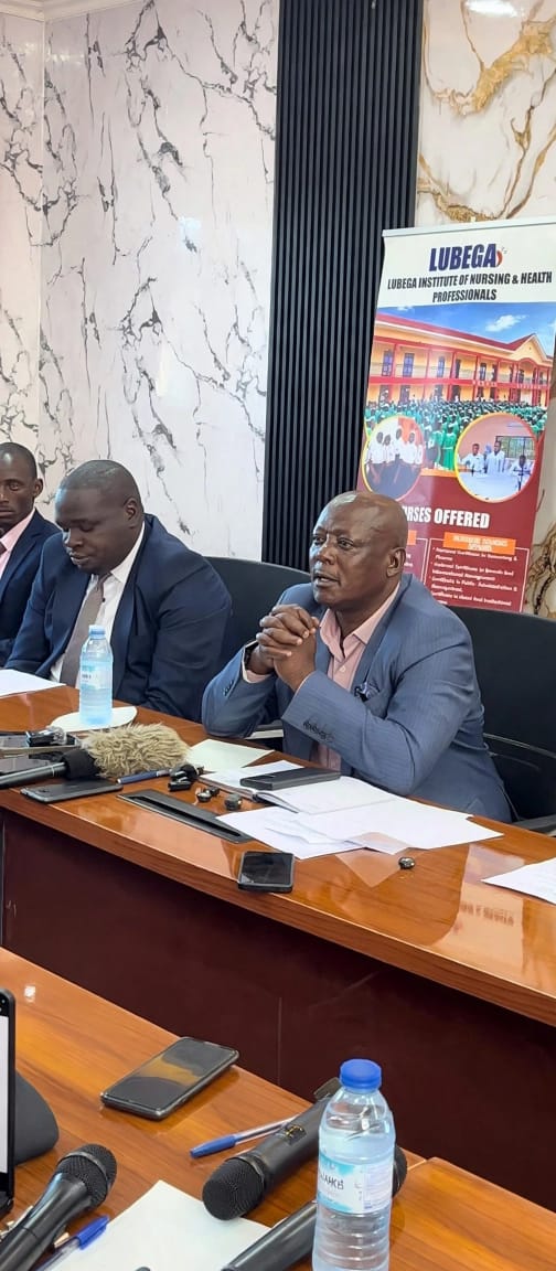 Prof. Dr. Muhamadi Lubega Kisambira, Director of Lubega Institute, in a blue coat, standing with the institution’s legal officer during a press conference on alleged tuition fraud.